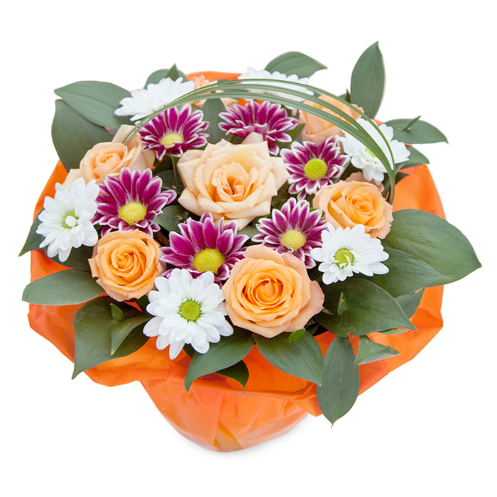 In this aerial view of a hand-crafted Whetstone floral bouquet, the artistry shines against a crisp white canvas, reflecting both modern design and traditional care found in N20's finest flower shops. Nestled at the bouquet's core, several roses unfurl in varying stages, moving from soft apricot to vivid orange and exuding a gentle fragrance typical of locally sourced blooms during early summer. Threaded among them are crispy white chrysanthemum sprays, their daisy-like faces highlighted by bright, grassy-green centres, pairing delicately with jewel-toned magenta chrysanthemums that shimmer with golden-lime hearts. Voluminous clusters of glossy, emerald green foliage create an embrace around the central arrangement, their broad leaves echoing the mature trees of Whetstone's public gardens. Light spools of bright green bear grass arch elegantly above, casting soft lines that guide the viewer's eye across the layered structure. The bouquet is secured with a wrap of luminous orange cellophane at the base, its cheerful hue amplifying the energy of the roses. This lush arrangement, ideal for nearby celebrations or heartfelt occasions, embodies the careful hands and thoughtful eye of Whetstone florists, providing beauty and joy that seem to carry the gentle promise of local gatherings, summer birthdays, or spontaneous acts of kindness along Totteridge Lane.